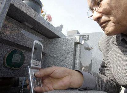Teruo Oba escanea con su móvil el código de barras de la tumba familiar.