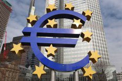 Logotipo gigante de la eurozona frente a la torre del Banco Central Europeo.