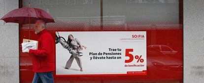 Una persona pasa delante de un anuncio de planes de pensiones.