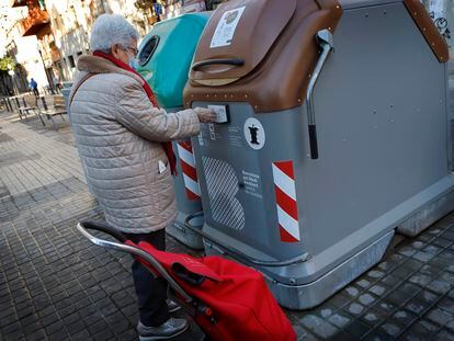 Una vecina de Sant Andreu abre uno de los nuevos contenedores inteligentes para basura orgánica.