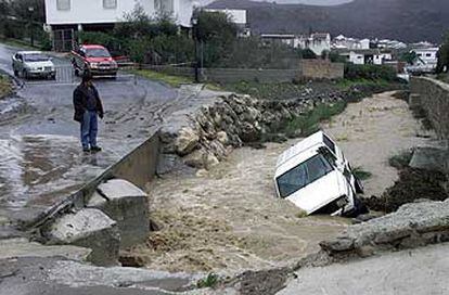 Un hombre observa el coche del hombre desaparecido en Riogordo, que fue arrastrado por un arroyo que pasa por el municipio.