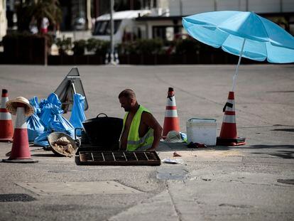 Un trabajador se protege del sol con una sombrilla en Valencia, el jueves.