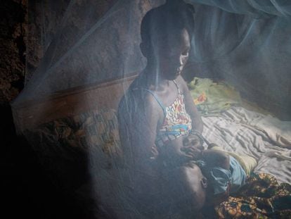 Una madre amamanta a su bebé bajo una mosquitera, en Sierra Leona. 