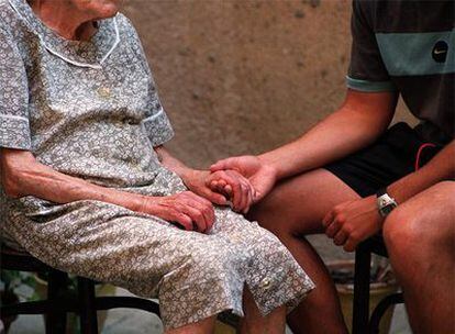 Un voluntario de Cruz Roja atiende a una anciana en su domicilio de Madrid.