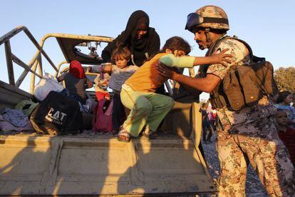 Una foto muestra a un soldado jordano ayudando a entrar en su pa&iacute;s a refugiados sirios.
