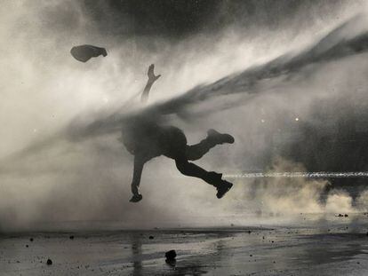 Una manifestante recibe el golpe de un chorro de agua durante una manifestación de protesta realizada en Santiago el 9 de diciembre.