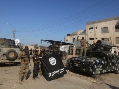 Uns iraquians mostren victoriosos una bandera de l'ISIS després de recuperar Ramadi.