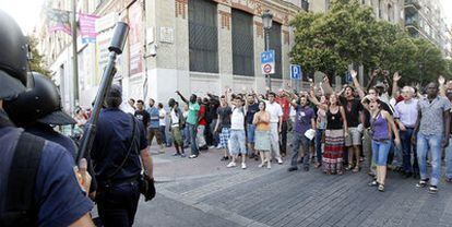 Los vecinos de Lavapiés e indignados del 15-M increpan a los policías antidisturbios en la calle de Valencia.