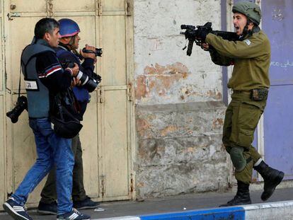 Un soldado israelí apunta con su arma junto a dos reporteros, el pasado diciembre en Hebrón (Cisjordania).