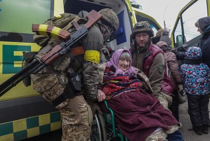 Dos soldados ucranios ayudan a evacuar a una mujer de Irpin, en las cercanías de Kiev.