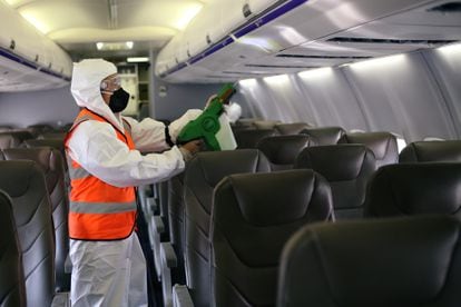 Un hombre desinfecta el interior de un avión en el Aeropuerto Internacional el Dorado, en Bogotá, Colombia.