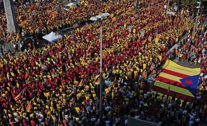 Mosaico de camisetas rojas y amarillas bajo un sol de justicia en el Paseo de Gracia de Barcelona.