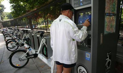 Un turista ante un tótem de BiciMAD en Retiro.