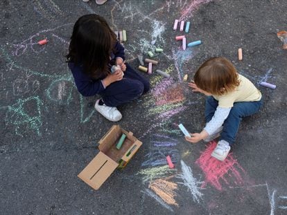 Dos niños juegan sobre el asfalto en una calle de Madrid.