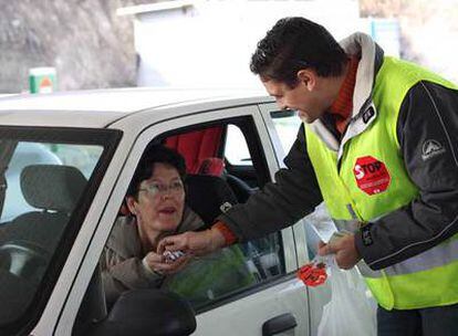 Un voluntario de Stop Accidentes habla con una conductora en una gasolinera de la autovía A-3.