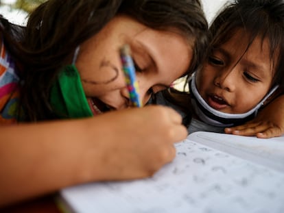 Keyla Vera (izq.) le enseña a Ariana Rodríguez matemáticas básicas durante las clases con Denisse Toala, una estudiante de 16 años, imparte debajo de un árbol a los que no pudieron asistir a clases virtuales durante la pandemia, en Guayaquil, Ecuador.