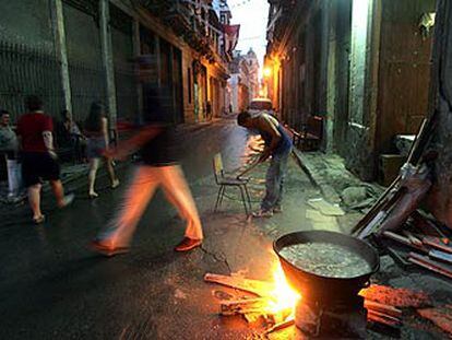 Transeúntes pasan junto a una olla de <i>caldosa,</i> un guiso típico cubano, en una calle de la Habana Vieja.