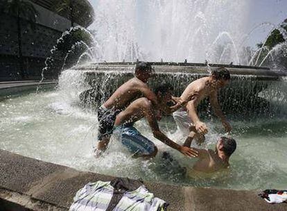 Unos jóvenes se refrescan, ayer, en una fuente de la avenida de la Palmera en Sevilla.