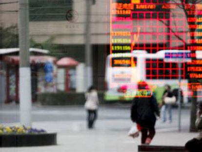 Un hombre mira un panel con valores de la Bolsa de Shangh&aacute;i.