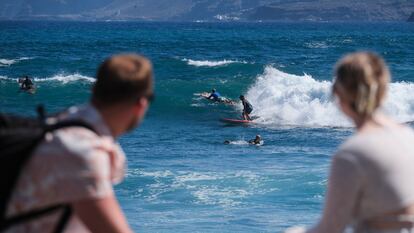 Dos turistas observan a los surfistas en el municipio tinerfeño de Puerto de la Cruz, el pasado 27 de septiembre.