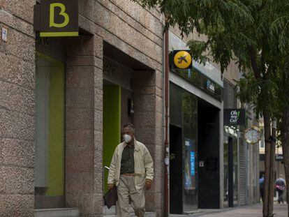 MADRID, SPAIN - SEPTEMBER 17: A man walks past branches of Bankia (L) and CaixaBank (R) on September 17, 2020 in Madrid, Spain. The Caixabank and Bankia merger will create Spain's biggest lender, with a market value of about 16bn euros and hold €600bn of assets. The proposed deal marks another round of mergers for Europe's banks struggling to cope with record low interest rates and the economic downturn sparked by the Covid-19 pandemic. (Photo by Pablo Blazquez Dominguez/Getty Images)