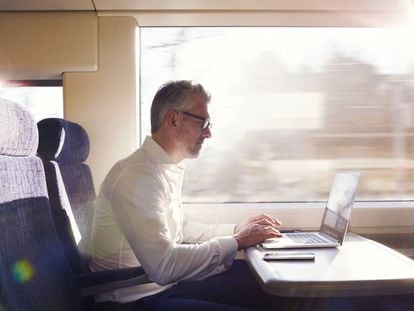 Un hombre trabaja en el ordenador mientras viaja en tren.