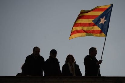 Un home sosté una bandera independentista des del terrat d'un edifici de Barcelona.