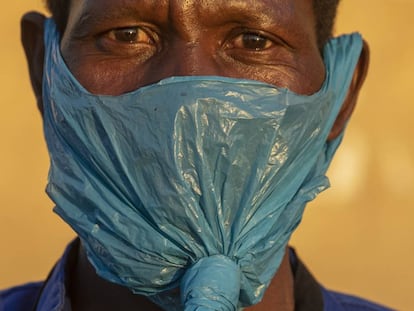Un hombre usa una bolsa de plástico en la cara como mascarilla facial contra la propagación del coronavirus, en Johannesburgo, Sudáfrica.