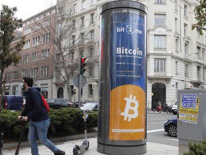 Un joven pasa junto a un panel de publicidad de bitcóin en Madrid