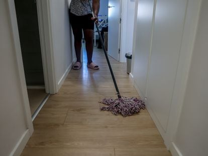 Una mujer friega el pasillo de casa en Madrid.