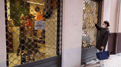 Una mujer saluda desde la calle a otra mujer en el interior de una tienda en el centro de Málaga.