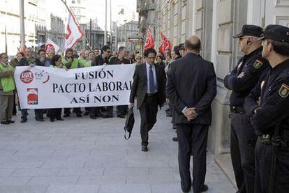 Un miembro de la asamblea de Caixanova pasa ante los opositores a la fusión que se concentraron ayer ante la sede de la caja.