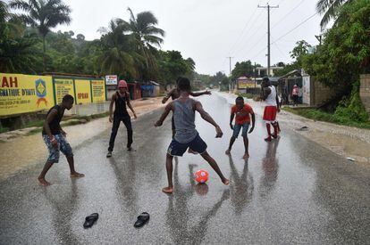 Un grup de joves juga a futbol sota la pluja en una carretera camí a Leogane, al sud de Port-au-Prince (Haití).