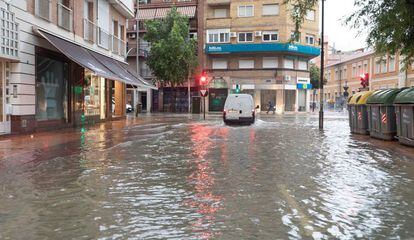 Un coche circula esta mañana por la calle Princesa de Murcia, inundada tras las intensas lluvias.