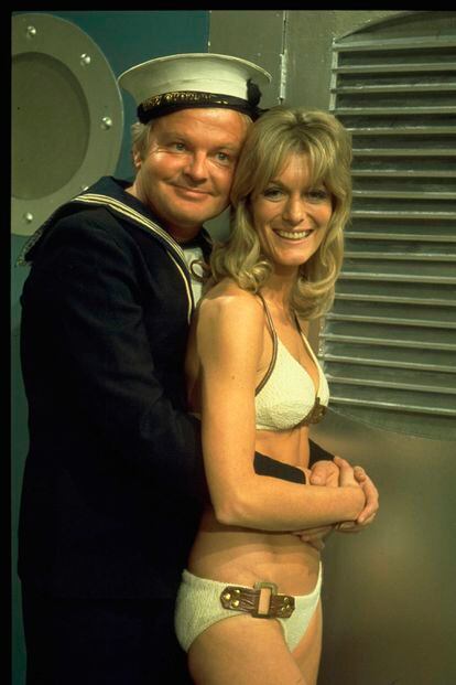 Benny Hill disfrazado de marinero y abrazando a una mujer en bikini alrededor de 1970. La estampa del cómico junto a mujeres ligeras de ropa era habitual en la serie.