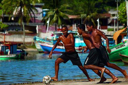 Tres chicos se disputan la pelota en la playa de los pescadores, en Itaipava. La ciudad está al sur del estado de Espírito Santo.