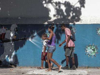 Una familia pasa por delante de un grafiti que muestra a un sanitario rociando coronavirus con la cara del presidente Jair Bolsonaro, el 22 de junio.
