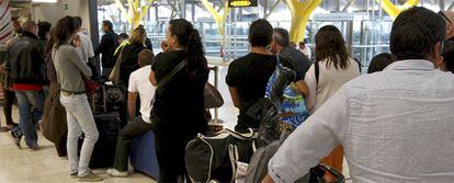 Un grupo de pasajeros hace cola ante el mostrador de atención al cliente de Iberia en Barajas.