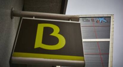 Un cartel con el símbolo de Bankia delante del logo de Caixabank tras su sustitución por el de Bankia en las torres Kio, en Madrid (España).