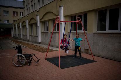 Yarik balancea a su hermana Yana en el patio del hospital público de Lviv.  