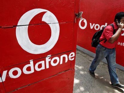 Un hombre habla por el m&oacute;vil al lado de los carteles de Vodafone