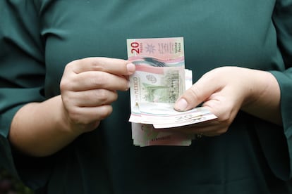 hands of a woman holding and counting mexican banknotes of twenty pesos