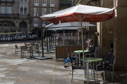 Un hombre fuma sentado en una terraza en la Plaza Mayor de Ourense.