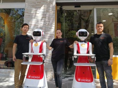 Tres empleados y dos robots del restaurante valenciano Crensa a las puertas del establecimiento. En vídeo, las máquinas en acción.