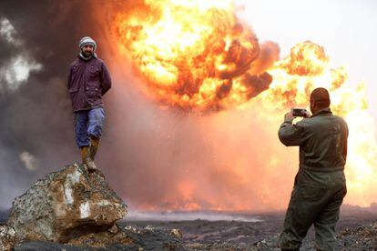 Un hombre hace una fotografía a su amigo frente a una explosión provocada por el Estado Islámico de un pozo petrolífero antes de huir de la región Qayyara (Irak), el 29 de enero.
