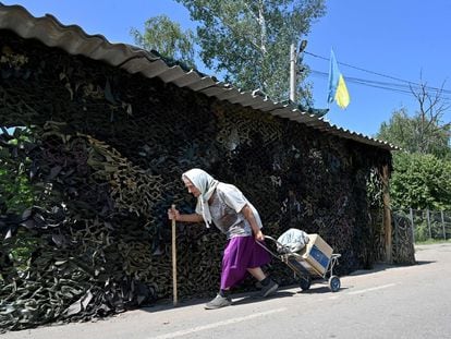 Una mujer lleva una caja de comida del Programa Mundial de Alimentos de la ONU, distribuidos por voluntarios, como ayuda humanitaria a los residentes locales de la aldea de Liptsy, región de Kharkiv, a unos 10 km de la frontera con Rusia, el 22 de junio de 2023,