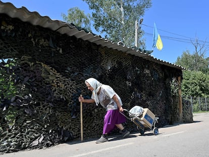 Una mujer lleva una caja de comida del Programa Mundial de Alimentos de la ONU, distribuidos por voluntarios, como ayuda humanitaria a los residentes locales de la aldea de Liptsy, región de Kharkiv, a unos 10 km de la frontera con Rusia, el 22 de junio de 2023,