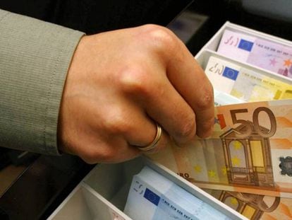 Un empleado de banca muestra un billete de 50 euros.