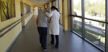 Una especialista ayuda a caminar a un enfermo de alzheimer en el centro CRE de Salamanca.