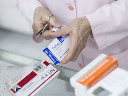 Una farmac&eacute;utica sirve medicamentos a unos clientes en una botica de Barcelona. 